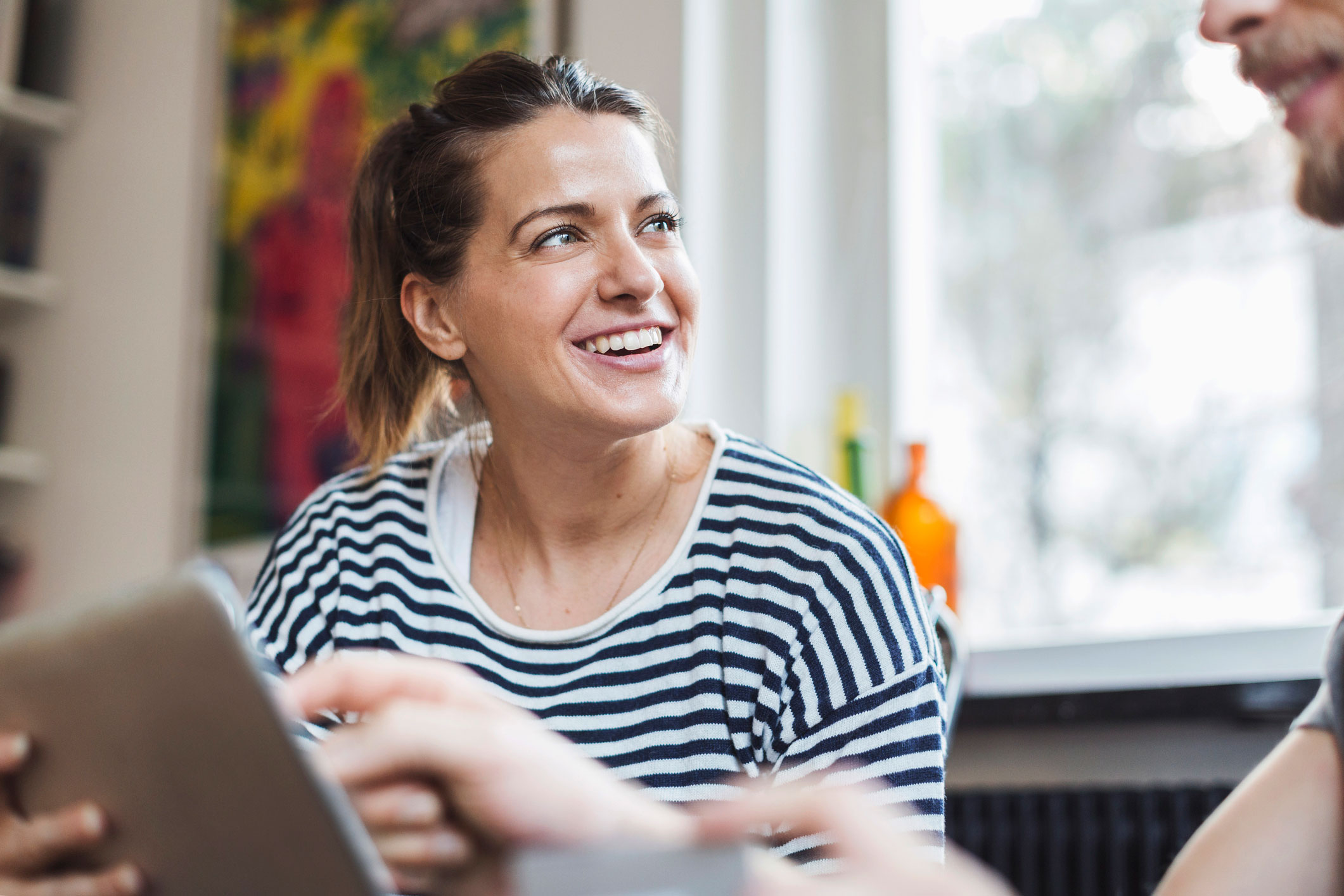 Kvinne med stripete genser som snakker med man med ipad